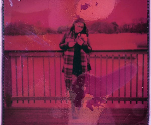 Photographie artistique teintée de rose d'une personne debout près d'une balustrade à l'extérieur.