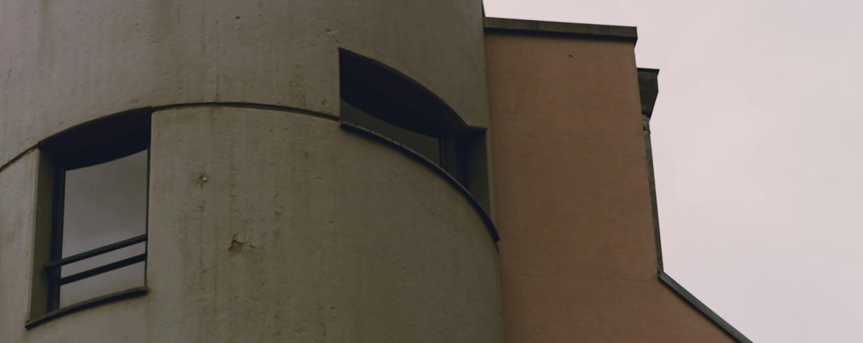 Un bâtiment contemporain présentant des formes cylindriques et des motifs géométriques sur un ciel maussade.